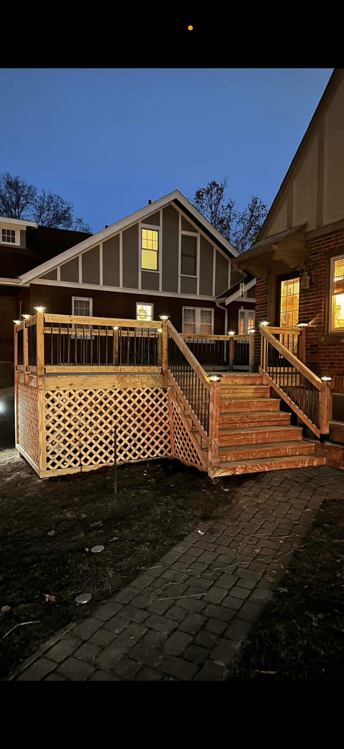 New wooden deck with lattice skirting, illuminated stairs, and railing lights at dusk.